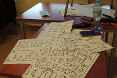 Stół na którym znajdują się kartki z rysunkami