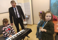 Dziewczynka  gra na keyboardzie, wykładowca nadzoruje grę