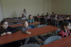 dzieci siedzące w ławkach