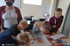 prof. Stawiak-Ososińska i dzieci wykonujące plakat