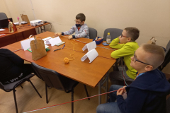 Chłopcy siedzący przy stole i trzymający włóczkę