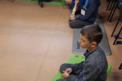 Dzieci siedzące na matach i trzymające nogi