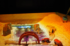 kuweta z piaskiem, a w niej samochody, budynki i most