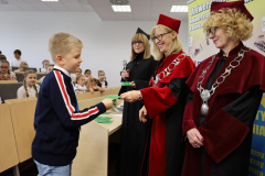Pani Rektor i Pani Dziekan wręczające indeks chłopcu