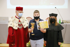 JM Rektor UJK prof. dr hab. Stanisław Głuszek, dr hab. Anna Wileczek, prof. UJK i chłopiec podczas odbioru dyplomu