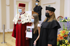 JM Rektor UJK prof. dr hab. Stanisław Głuszek, dr hab. Anna Wileczek, prof. UJK i dziewczynka  odbierający dyplom