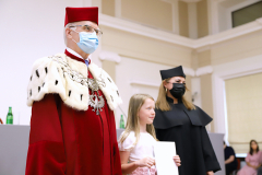 JM Rektor UJK prof. dr hab. Stanisław Głuszek, dr hab. Anna Wileczek, prof. UJK i dziewczynka  odbierający dyplom