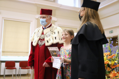 JM Rektor UJK prof. dr hab. Stanisław Głuszek, dr hab. Anna Wileczek, prof. UJK i dziewczynka  odbierający dyplom
