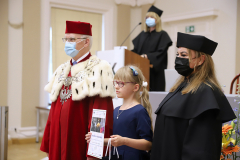 JM Rektor UJK prof. dr hab. Stanisław Głuszek, dr hab. Anna Wileczek, prof. UJK i dziewczynka  odbierający dyplom