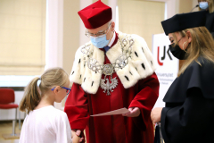 JM Rektor UJK prof. dr hab. Stanisław Głuszek, dr hab. Anna Wileczek, prof. UJK i dziewczynka  odbierający dyplom