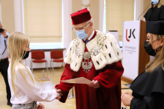 JM Rektor UJK prof. dr hab. Stanisław Głuszek, dr hab. Anna Wileczek, prof. UJK i dziewczynka  odbierający dyplom